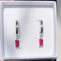 Silver earrings with ruby gemstones in a white box