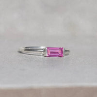 Silver ring with a pink sapphire gemstone on a light grey background