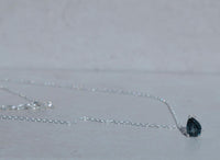 Necklace with a black teardrop-shaped pendant on a light gray background
