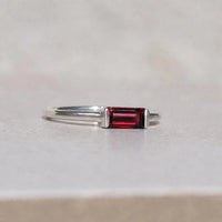 Silver ring with a red garnet gemstone on a light gray background