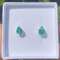 Teardrop-shaped green gemstone earrings in a white jewellry box.