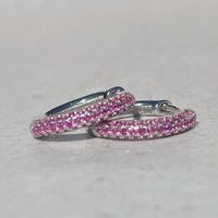Pair of pink hoop earrings on a light gray background